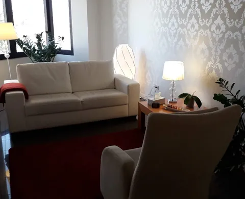 Sala de consulta d'Anna Serentill, amb un sofà blanc, una butaca i llum càlida